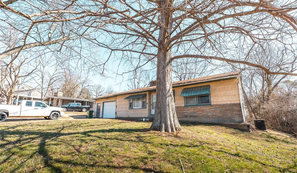 ranch-style house featuring stone siding, a front lawn, a chimney, and an attached garage