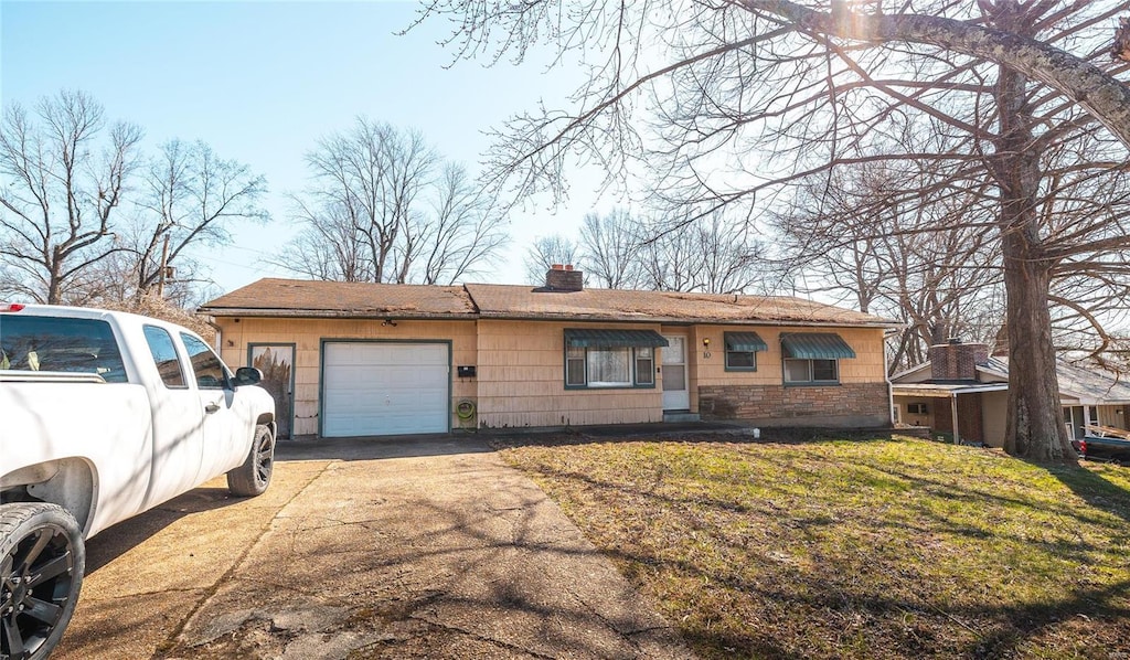 ranch-style home with an attached garage, a chimney, a front lawn, and concrete driveway