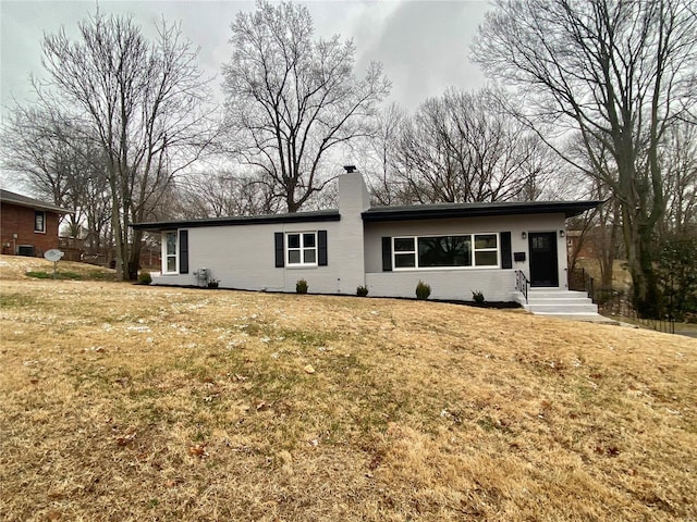 back of property with a yard, brick siding, and a chimney