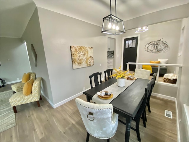 dining area with light wood-type flooring, visible vents, and baseboards