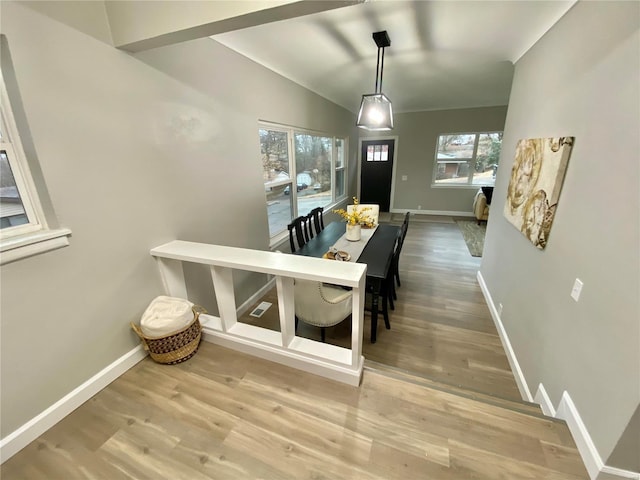 dining space featuring vaulted ceiling, baseboards, and wood finished floors