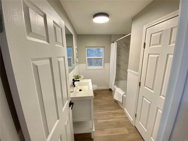 full bath with shower / tub combo, wainscoting, toilet, wood finished floors, and vanity