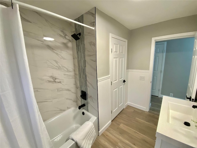 full bathroom featuring a wainscoted wall, wood finished floors, vanity, and shower / tub combo with curtain