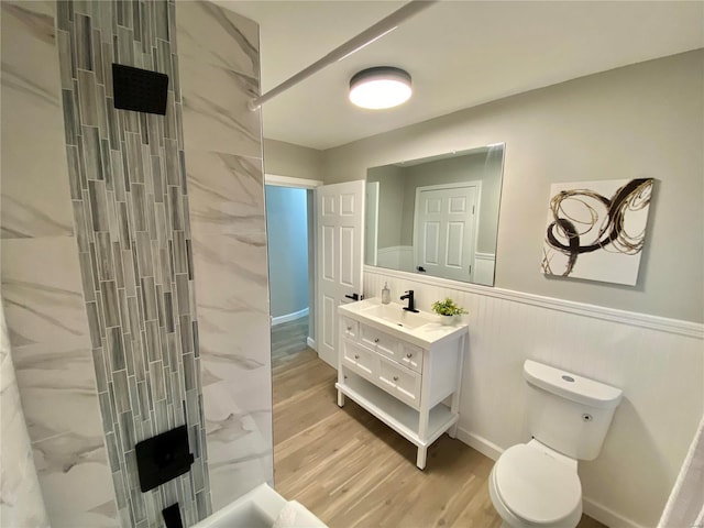 full bathroom featuring a shower, toilet, a wainscoted wall, wood finished floors, and vanity