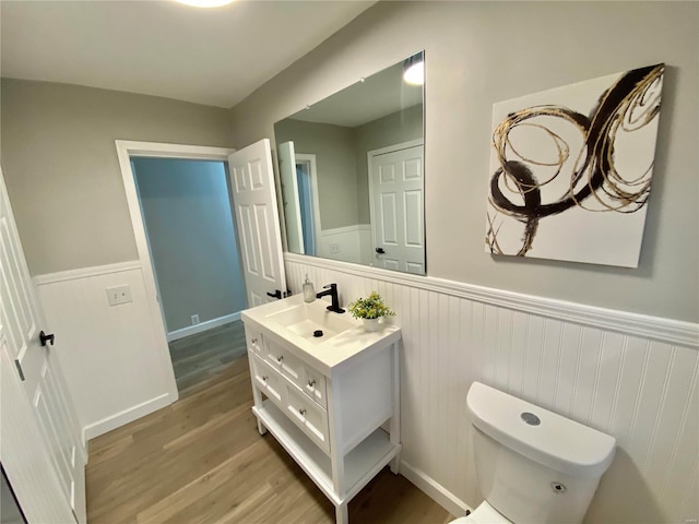 bathroom featuring wainscoting, vanity, toilet, and wood finished floors