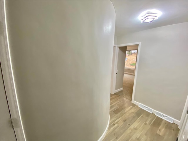 corridor featuring light wood-type flooring and baseboards