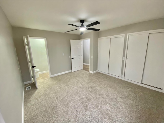 unfurnished bedroom with carpet floors, two closets, visible vents, and baseboards