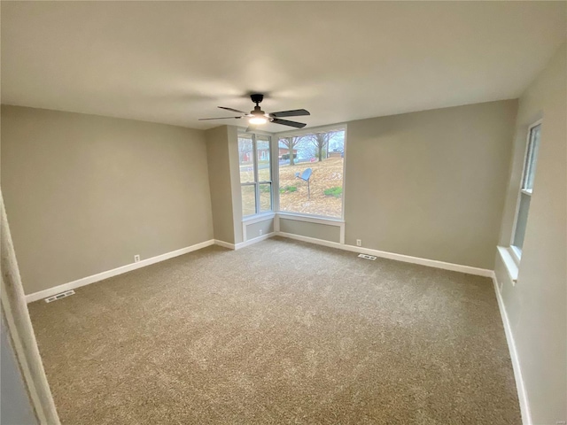 carpeted spare room with ceiling fan, visible vents, and baseboards