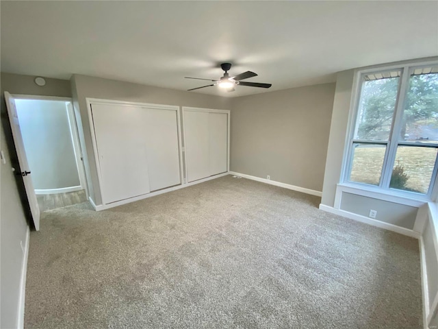 unfurnished bedroom with baseboards, ceiling fan, carpet, and multiple closets