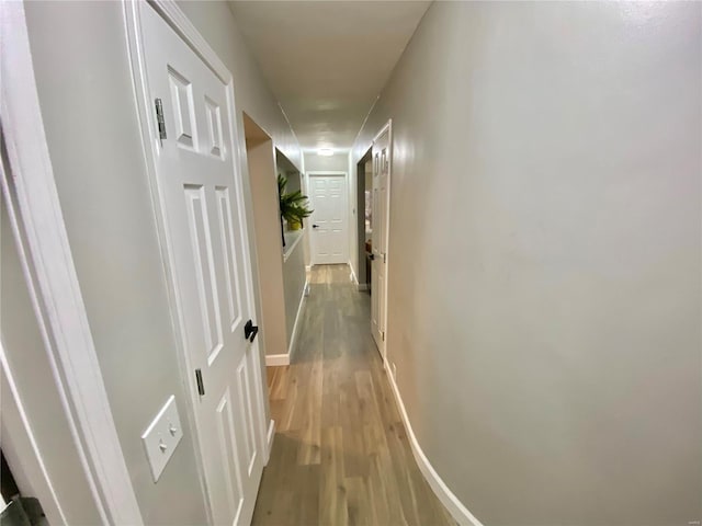 corridor with baseboards and wood finished floors