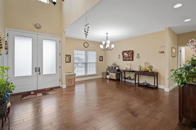 foyer featuring dark wood-style flooring, baseboards, a notable chandelier, and french doors