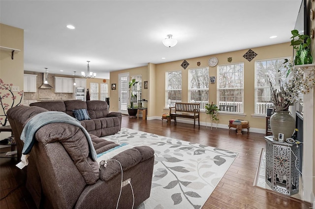 living room featuring recessed lighting, a notable chandelier, baseboards, and hardwood / wood-style flooring