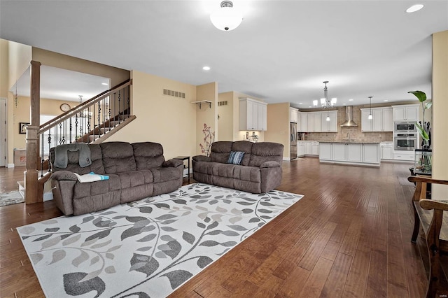 living area with dark wood-style floors, a notable chandelier, recessed lighting, visible vents, and stairs