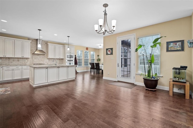 kitchen featuring dark wood-style floors, wall chimney exhaust hood, backsplash, and stainless steel appliances