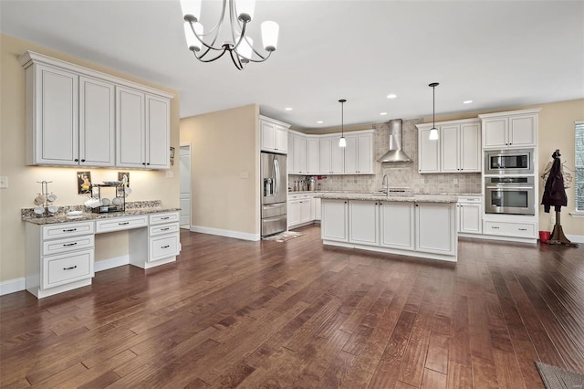 kitchen with appliances with stainless steel finishes, dark wood-type flooring, built in study area, a sink, and wall chimney range hood