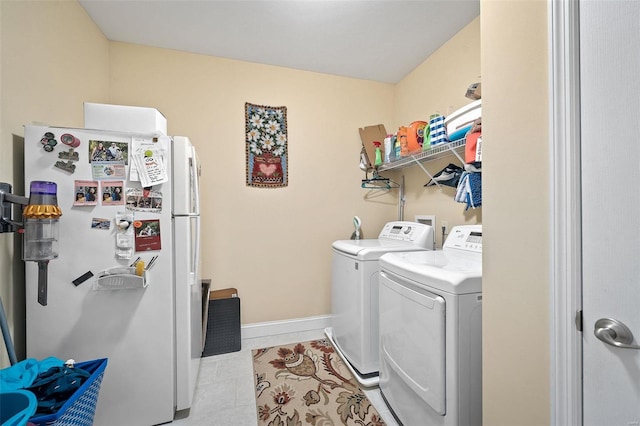 clothes washing area featuring laundry area, washing machine and dryer, baseboards, and tile patterned floors