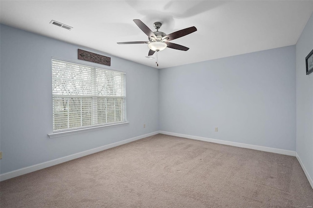 spare room featuring carpet, visible vents, ceiling fan, and baseboards