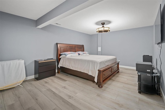 bedroom with light wood finished floors, baseboards, visible vents, and beamed ceiling