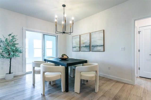 dining room with a notable chandelier, light wood-type flooring, and baseboards