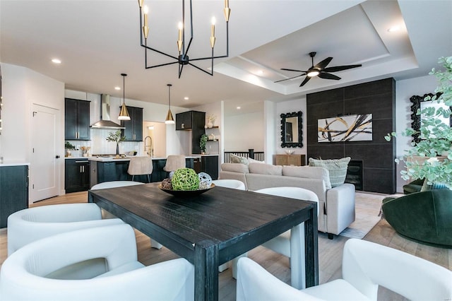 dining area with light wood-style flooring, a tray ceiling, a ceiling fan, and recessed lighting