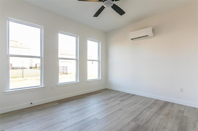 empty room featuring light wood-style floors, a wall mounted air conditioner, baseboards, and a ceiling fan