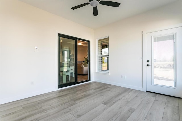 spare room featuring baseboards, light wood-style flooring, and a healthy amount of sunlight