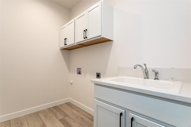 clothes washing area with hookup for a washing machine, a sink, cabinet space, light wood finished floors, and electric dryer hookup