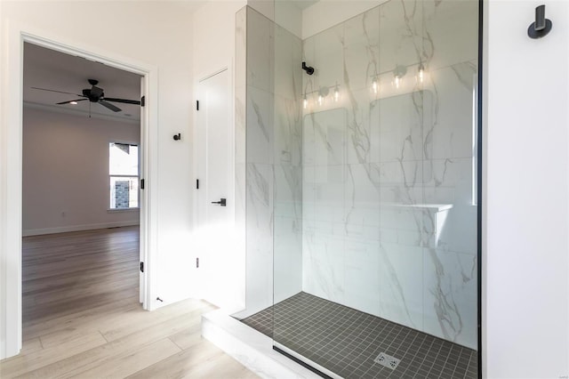 bathroom with ceiling fan, wood finished floors, a marble finish shower, and baseboards