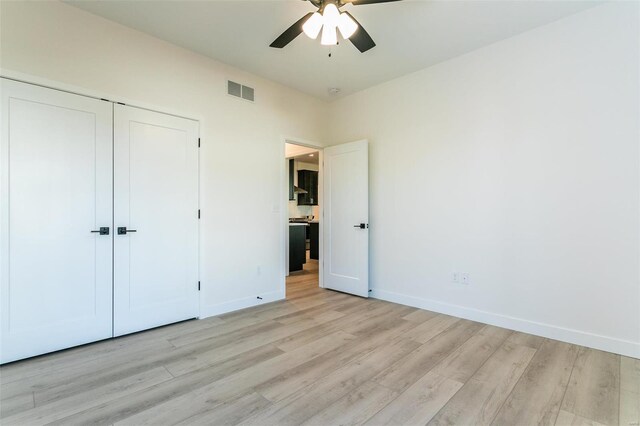 unfurnished bedroom with baseboards, visible vents, a ceiling fan, light wood-style floors, and a closet