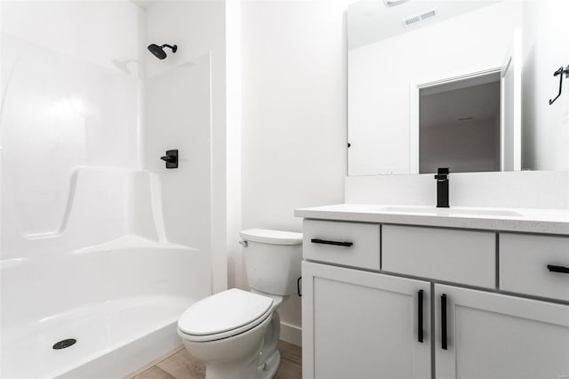 bathroom with toilet, wood finished floors, vanity, visible vents, and a shower