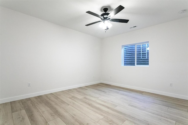 spare room featuring light wood finished floors, visible vents, baseboards, and a ceiling fan