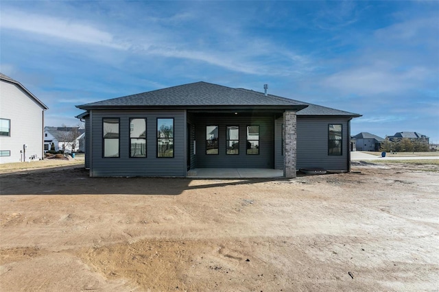 rear view of property featuring roof with shingles and a patio