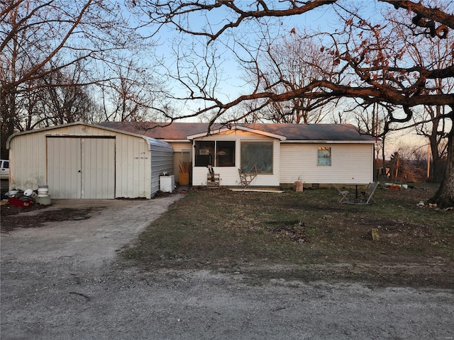 manufactured / mobile home with a sunroom, a garage, an outdoor structure, crawl space, and driveway