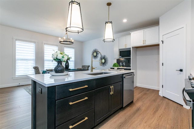 kitchen featuring stainless steel appliances, an island with sink, a sink, and light countertops