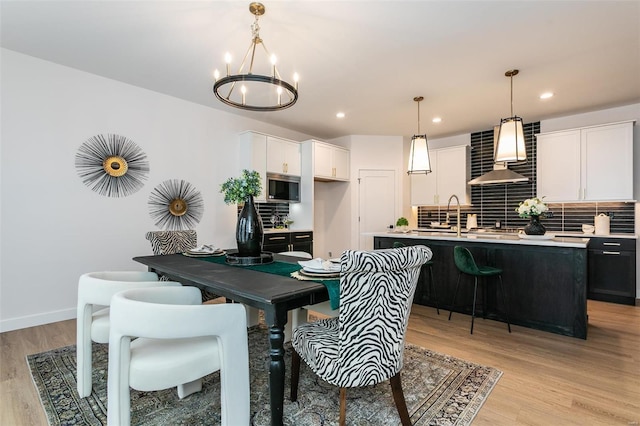 dining space featuring baseboards, light wood finished floors, recessed lighting, and an inviting chandelier