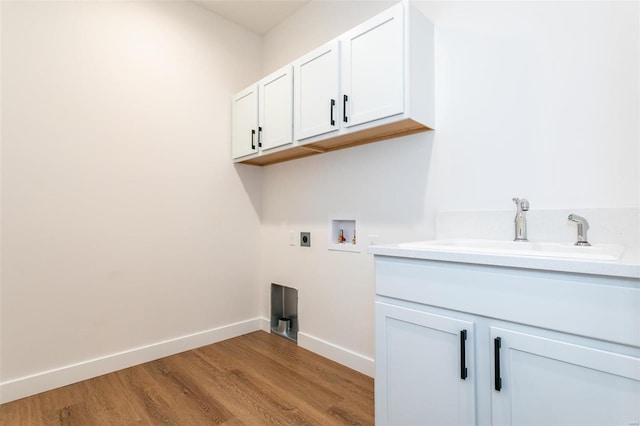 laundry room featuring cabinet space, hookup for an electric dryer, light wood-style floors, washer hookup, and a sink