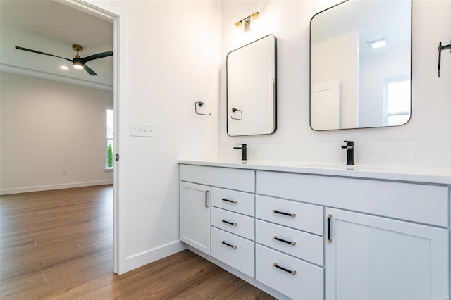 bathroom featuring double vanity, baseboards, ceiling fan, wood finished floors, and a sink