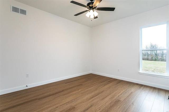 unfurnished room with dark wood-style floors, a ceiling fan, visible vents, and baseboards