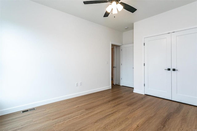 unfurnished bedroom with baseboards, visible vents, a ceiling fan, light wood-type flooring, and a closet