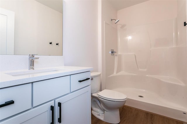 bathroom with vanity, walk in shower, wood finished floors, and toilet