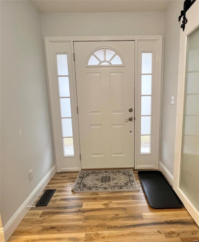 entryway featuring a barn door, plenty of natural light, wood finished floors, and visible vents