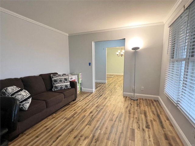 living room featuring a notable chandelier, baseboards, ornamental molding, and wood finished floors