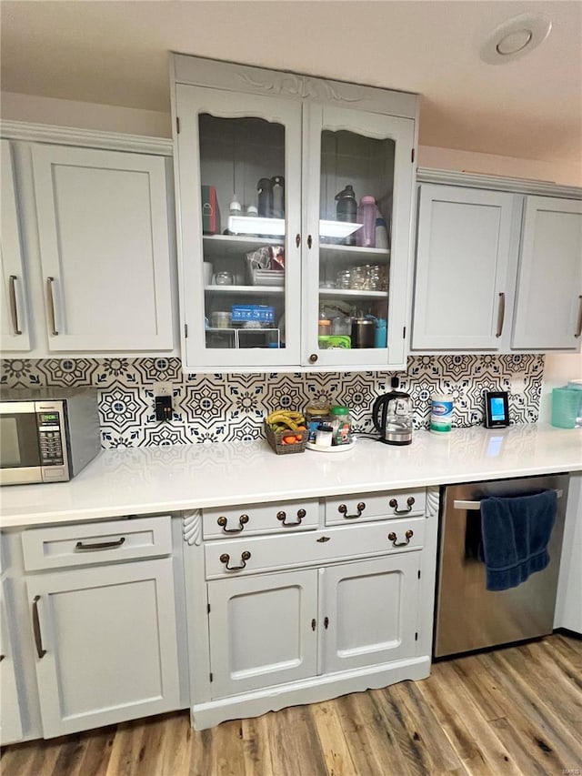 kitchen with stainless steel appliances, light wood-type flooring, and light countertops