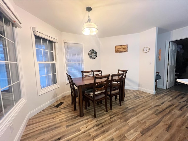 dining area with wood finished floors, visible vents, and baseboards