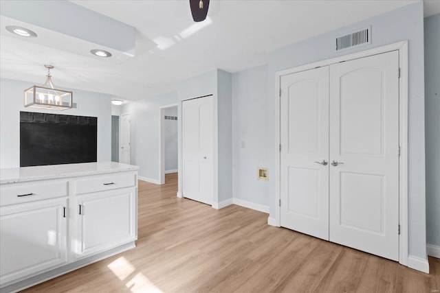 unfurnished living room with visible vents, baseboards, light wood-style floors, and a notable chandelier