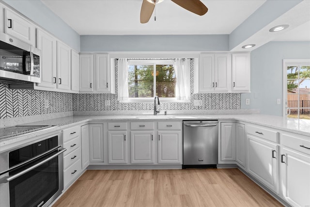 kitchen featuring a sink, stainless steel appliances, white cabinetry, and light wood finished floors