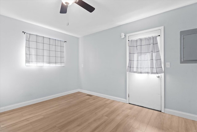 spare room with electric panel, ceiling fan, baseboards, and wood finished floors