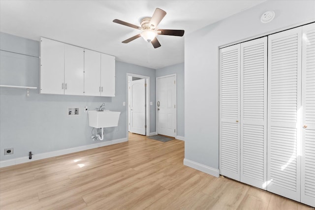 laundry room with light wood finished floors, baseboards, hookup for a washing machine, cabinet space, and a sink