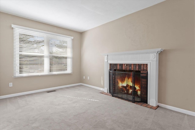 unfurnished living room featuring visible vents, baseboards, a warm lit fireplace, and carpet flooring