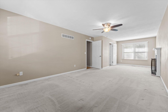 empty room featuring a glass covered fireplace, baseboards, visible vents, and light carpet